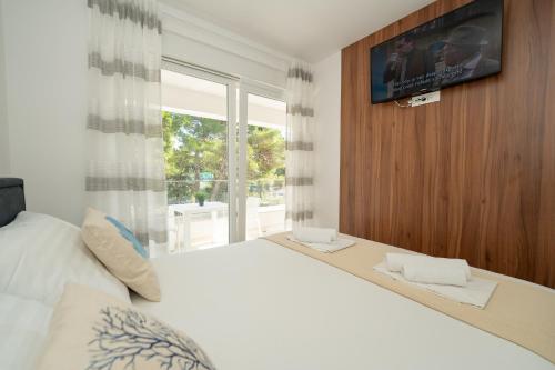 a bedroom with a large white bed and a window at Apartments Break with pool in Novalja