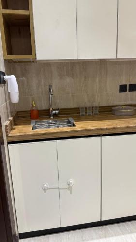 アル・カルジにあるشقق ضيافة البرجの白いキャビネットとシンクのあるキッチン