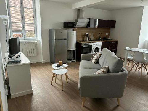 Una sala de estar con un sofá y una cocina. en Appartement, en Combronde