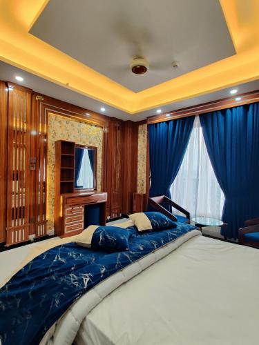 a large bed in a room with blue curtains at Qinwan Hotel & Suites in Rawalpindi
