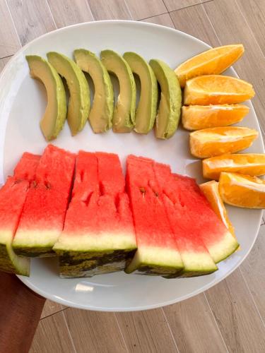 a white plate with slices of watermelon and pickles at A-Frame tiny house in Arusha