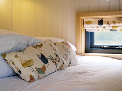 a bed with a pillow on it with a window at Lillie's Shepherds Hut at Shepherds Lodge Retreat and Wellness in Nottingham