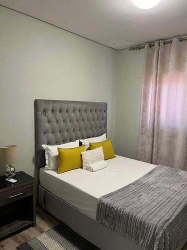 een slaapkamer met een groot bed met gele kussens bij Le grand hideout in Windhoek