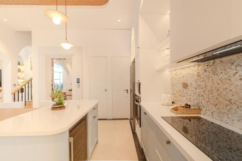 une cuisine avec des comptoirs et des placards blancs dans l'établissement Ha Long 6BRS Beach Villa With Pool, Jacuzzi and Sauna, à Hạ Long