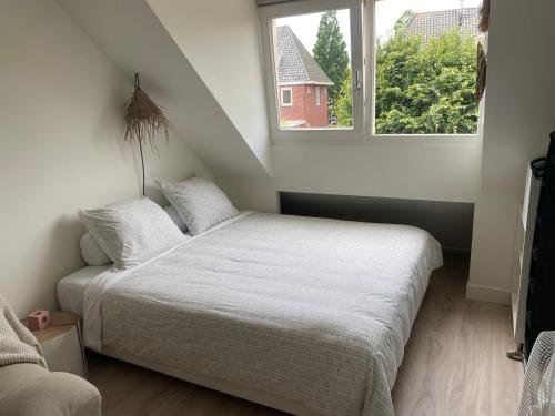 a bedroom with a white bed and a window at Appartement Buissant des Amorie! in Castricum