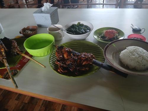 a table with plates of meat and rice on it at Bareng Homestay Tetebatu in Tetebatu