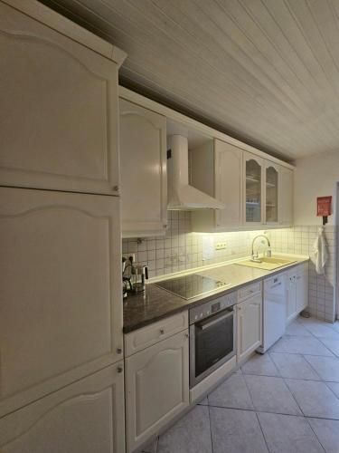 a kitchen with white cabinets and a sink and a refrigerator at Roschi's Gästehaus in Gudow
