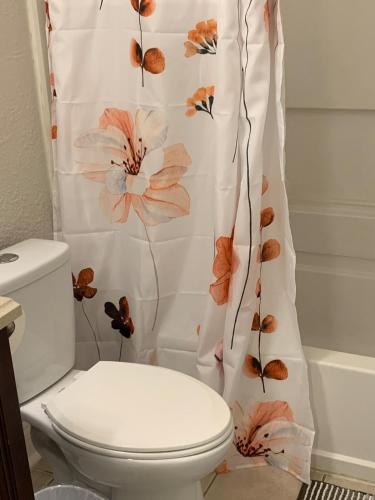 a bathroom with a toilet with a flower shower curtain at Runaway! in Charlotte