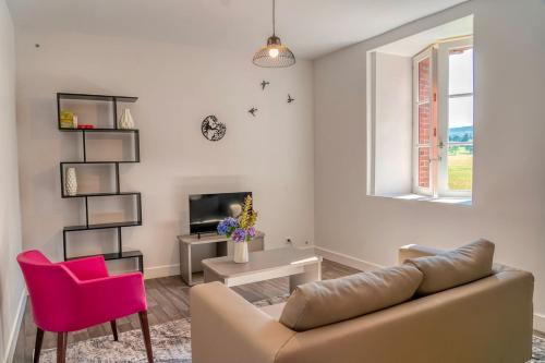 un salon avec un canapé et une chaise rose dans l'établissement House with a private hot tub and medieval garden, à Saint-Pierre-de-Frugie