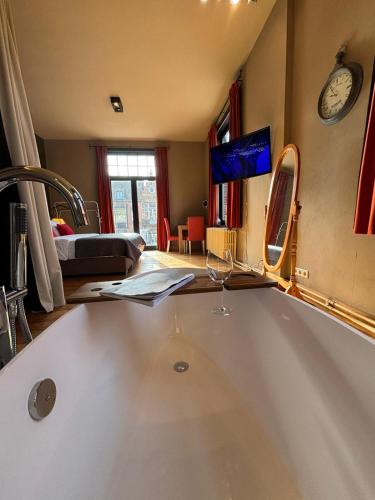 a bathroom with a tub and a sink and a bedroom at Maison du Rempart in Bruges