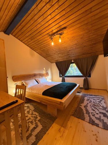 a bedroom with a large bed and a wooden ceiling at Cabana Arini 1954 in Vişeu de Jos