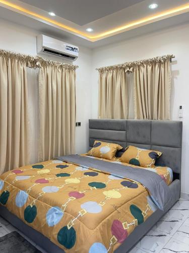 a bedroom with a bed with a yellow and blue blanket at Modern 3-Story Condo with Private Rooftop Lounge in Amasaman