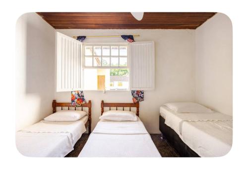 three beds in a room with a window at Casa Bromélia, a 15 minutos a pé do centro histórico! in Paraty