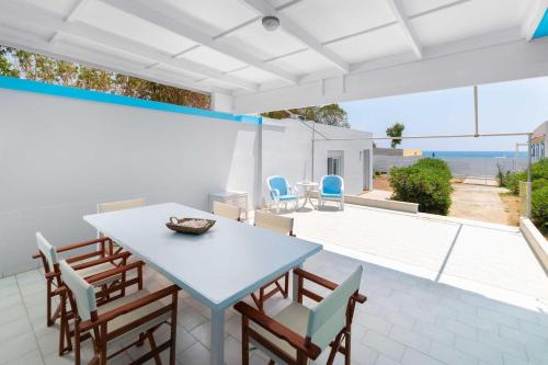 ein Esszimmer mit einem Tisch und Stühlen auf einer Terrasse in der Unterkunft The Cottage South Escape with beach front pool in Plimmiri