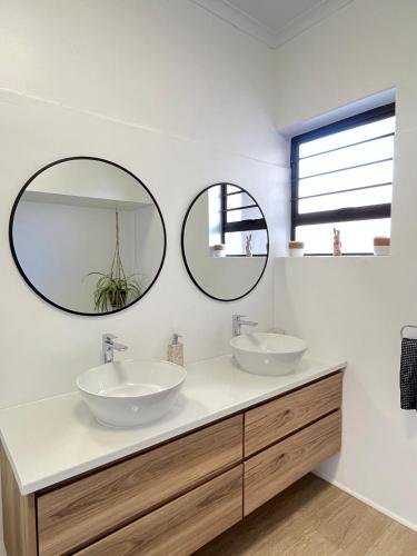 two sinks in a bathroom with two mirrors at Atlantic Apartment - spacious kite accommodation in Langebaan