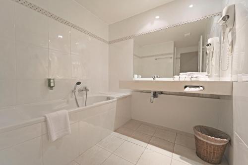 a white bathroom with a tub and a sink at Hôtel Panorama - Vue exceptionnelle sur la Semois in Bouillon