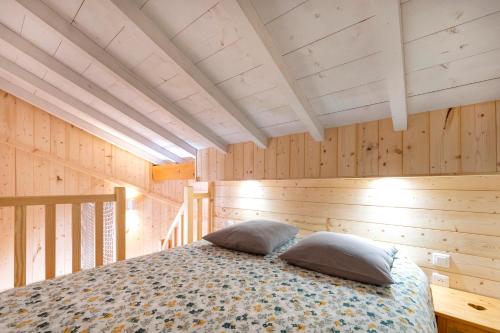 een slaapkamer met houten wanden en een bed met kussens bij goitik ikusita in Aïnhoa