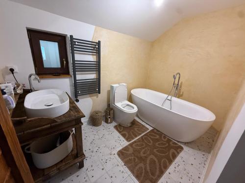 a bathroom with a tub and a toilet and a sink at Casutele de Poveste in Brădetu
