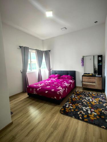 a bedroom with a pink bed and a rug at KAZ homestay in Tanah Rata