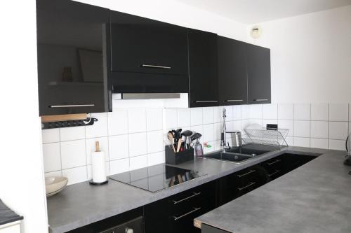 - une cuisine avec des placards noirs et un évier dans l'établissement Charmant appartement STRASBOURG, à Strasbourg