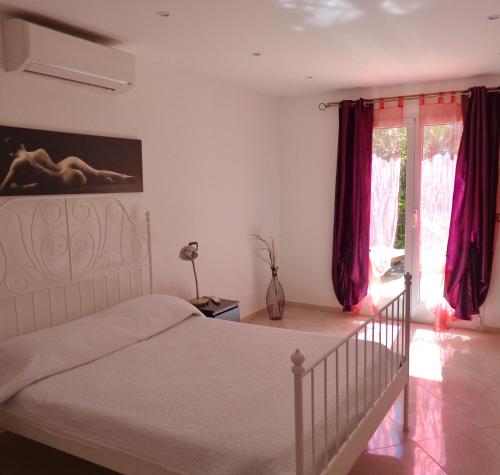 a bedroom with a white bed and red curtains at Villa sur mer, chez Angelina in Grimaud