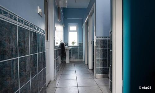 a hallway of a bathroom with green tiled walls at CECAS at Myross Wood House in Leap