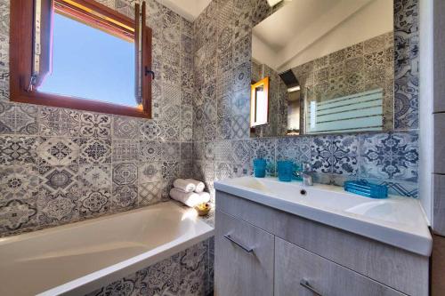 ein Badezimmer mit einem Waschbecken, einer Badewanne und einem Spiegel in der Unterkunft Villa Androniki in Longós