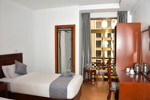 a bedroom with a bed and a desk and a table at Sun View Hotel in Addis Ababa