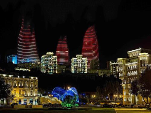 a city lit up at night with tall buildings at Fairmont Baku, Flame Towers in Baku