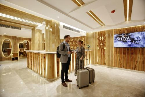 a man and woman standing in a hotel lobby with a suitcase at The Vanson Pride in New Delhi
