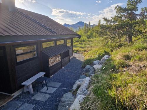 a small building with a bench next to a hill at Nordic View cabin 900m - Nær Gaustatoppen in Hjartdal