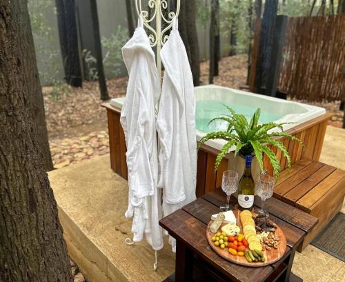a table with a plate of food and a bath tub at Luxury Tranquil Treehouse & Hot Tub in Pretoria