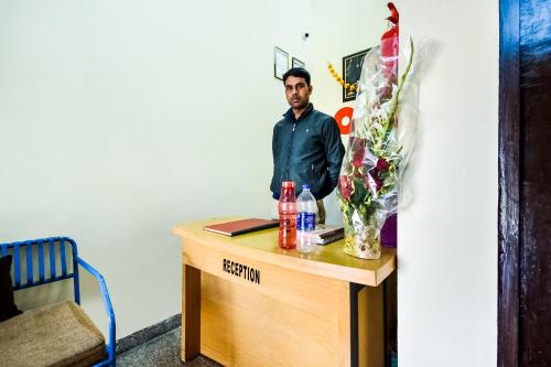 a man standing next to a table with flowers on it at Hotel O Prayag in Jaipur