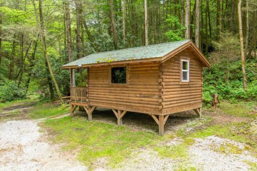 a log cabin with a porch in the woods at WiFi & Minimalist - Cozy Creek -Red River Gorge KY in Rogers