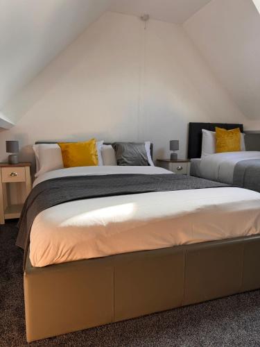 a bedroom with two beds with yellow pillows at Spacious Luxurious Serviced Accommodation 1 in Walsall