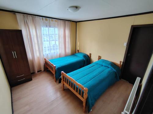 a room with two blue beds and a window at Subantartica Hostel House in El Cerrillo