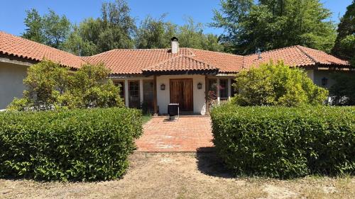 una casa con setos delante de ella en Countryside Retreat, en Peralillo