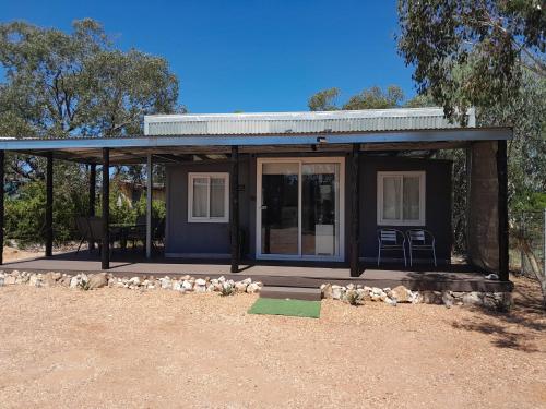 a small house with a porch and chairs in it at The Holiday Hut in Lightning Ridge