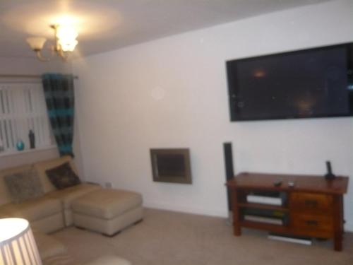 a living room with a couch and a flat screen tv at The Georgian Guesthouse in Alnwick