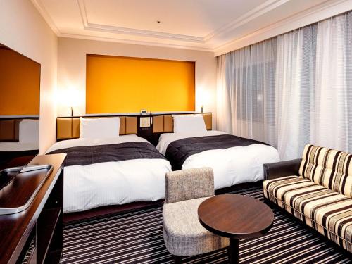 a hotel room with two beds and a couch at APA Hotel Fukuoka Watanabedori Ekimae EXCELLENT in Fukuoka