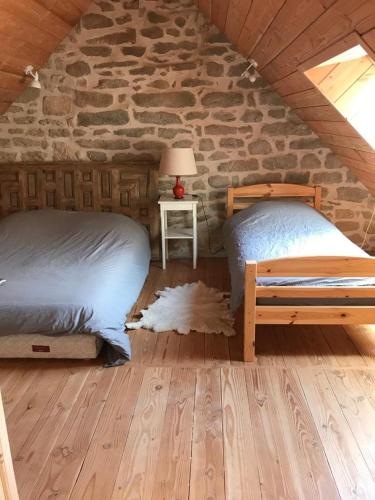 a bedroom with two beds and a stone wall at La maison de Baptiste La Monédière in Chaumeil
