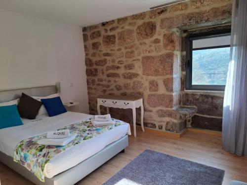 a bedroom with two beds and a window in a stone wall at Alqueiturismo - Casas de Campo in Guarda
