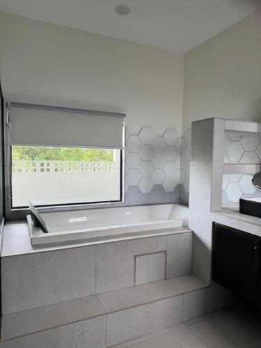 a white bathroom with a tub and a window at Micasa Bagan Laland,halal only in Tanjong Sepat