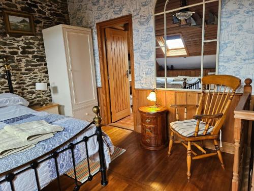 ein Schlafzimmer mit einem Bett und einem Stuhl und einem Fenster in der Unterkunft Rose by the sea - Beach front sea views in Hirel