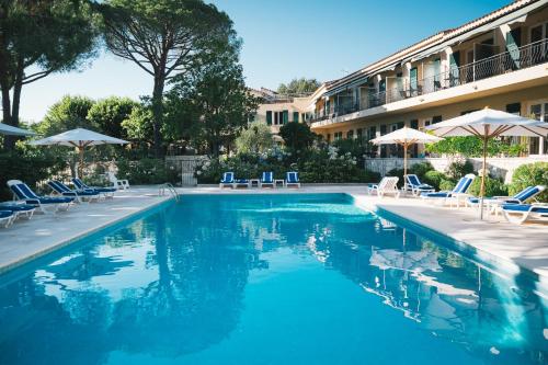 a swimming pool with chairs and umbrellas next to a hotel at Auberge du Rédier - Logis Hôtels in Colomars