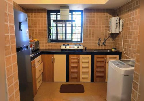 una pequeña cocina con encimera negra y ventana en 2bhk Villa - Calangute, en Candolim