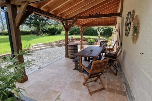 a patio with a wooden pergola with a wooden table and chairs at 3 Bed Cottage Sleeps 6 - Enclosed Patio -Fireplace in Beaucoudray