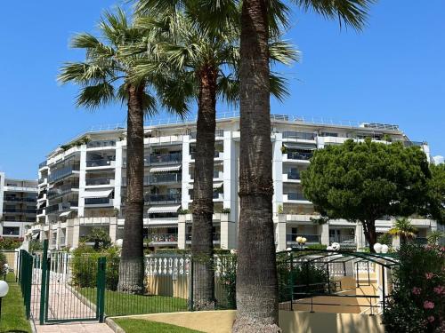 a building with palm trees in front of it at Le Lido - Piscine, proche plage in Cros-de-Cagnes
