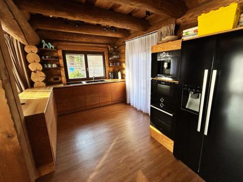 cocina con nevera negra y suelo de madera en Zrub Kováčová, en Kováčová