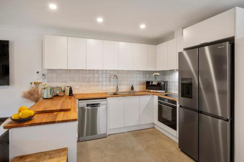 a kitchen with white cabinets and a stainless steel refrigerator at Chrissie's Cottage in Dunsborough